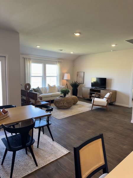 An inviting living area with modern decor, featuring a cozy sofa, patterned rug, and natural light through large windows.