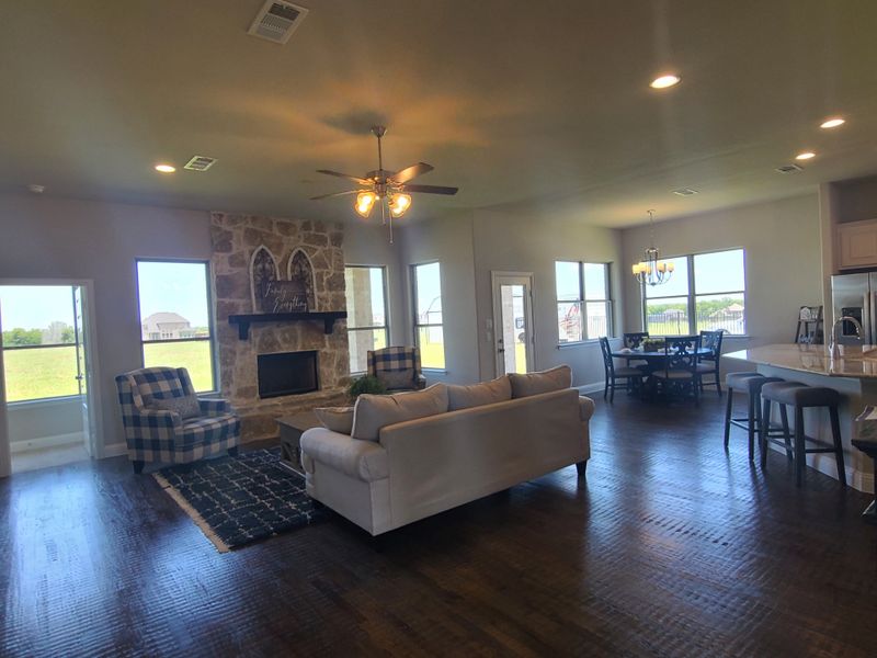 An inviting open-concept living area with stone fireplace, elegant dining space, and bright kitchen, perfect for entertaining.