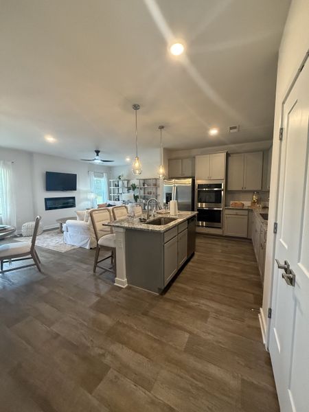 A modern kitchen with sleek cabinetry, a central island, and pendant lighting, leading to a cozy living area. A modern kitchen with sleek cabinetry, a central island, and pendant lighting, leading to a cozy living area.
