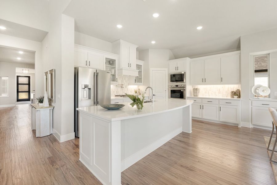 Open kitchen with white cabinets, large center island, stainless steel appliances, and light wood floors