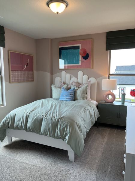 A cozy bedroom with a unique headboard, modern artwork, and soft, neutral tones.