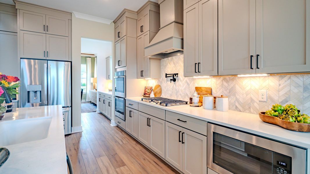 Kitchen with tile backsplash, quartz countertops, and pendant lighting Kitchen with tile backsplash, quartz countertops, and pendant lighting