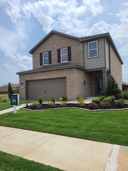 A modern brick home with a manicured lawn in Creekview Fossil Ridge by Starlight Homes (Pilot Point, TX).