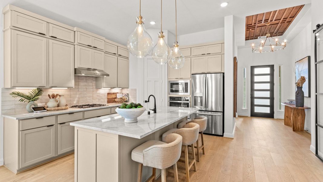 Bright designer kitchen featuring a large granite island with a stylish backsplash and modern finishes.