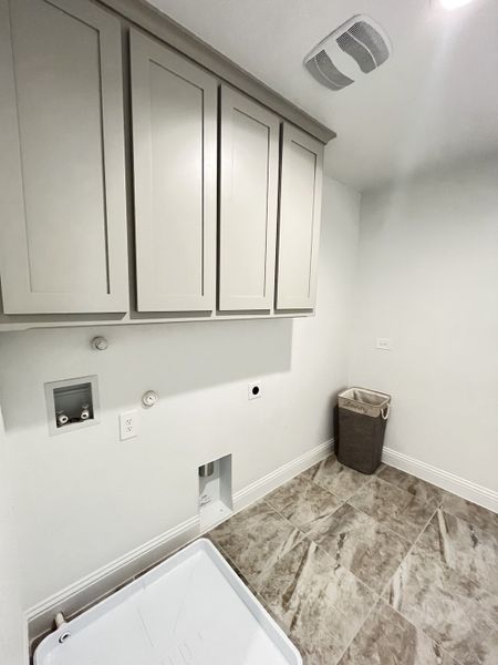 A sleek laundry room featuring gray cabinetry, tiled flooring, and a convenient hamper. A sleek laundry room featuring gray cabinetry, tiled flooring, and a convenient hamper.