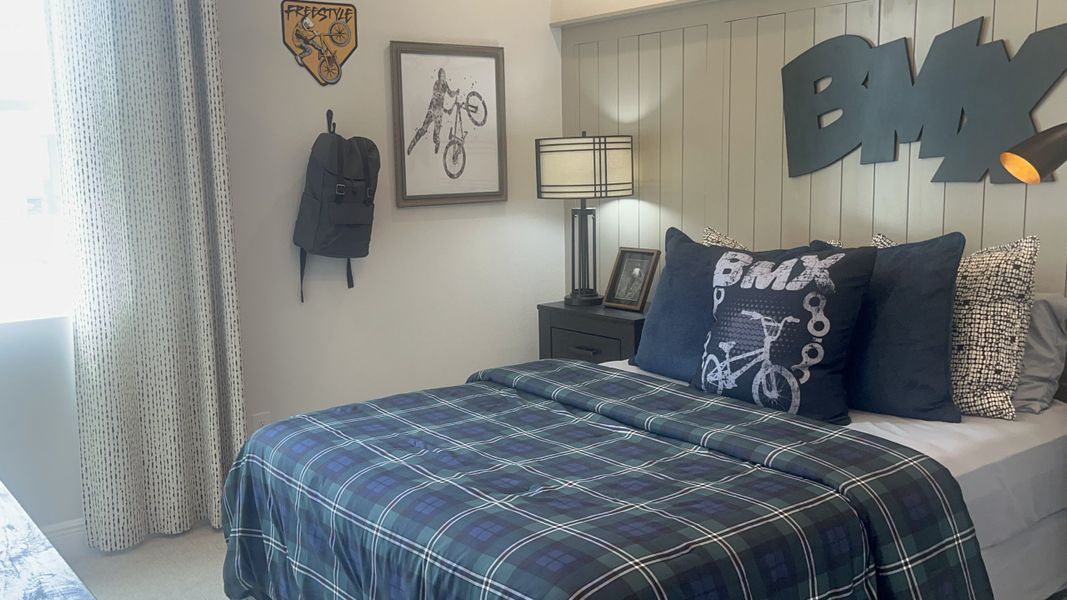 A cozy BMX-themed bedroom featuring plaid bedding, sports decor, and a stylish lamp for a lively atmosphere.