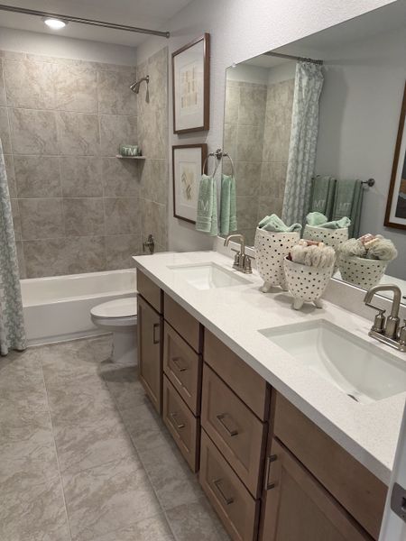 A modern bathroom features a double vanity, sleek fixtures, and elegant tiled walls, creating a spa-like retreat.