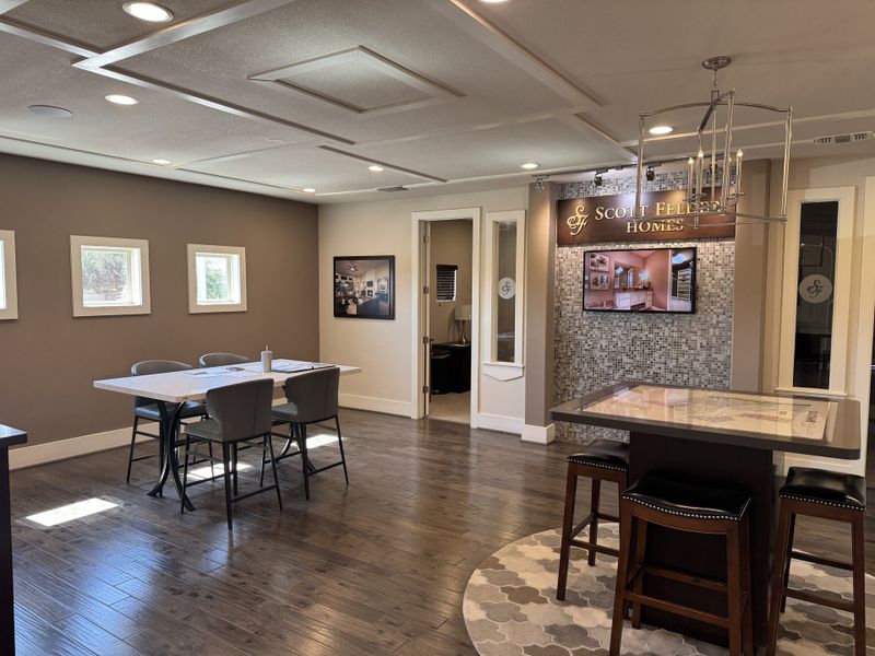 A modern meeting space with dark wood floors, cozy seating, and chic lighting, featuring Scott Felder Homes branding.