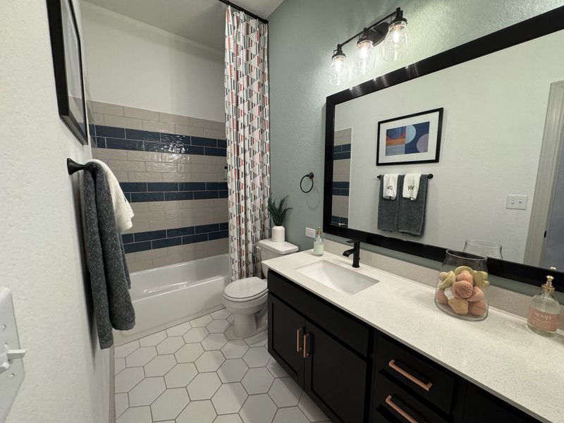 Modern bathroom with hexagonal tiles, sleek black vanity, artistic shower tiles, and stylish lighting.