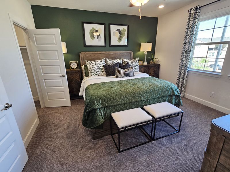 A cozy bedroom featuring a green accent wall, elegant decor, and plush bedding with patterned drapes for a stylish touch.