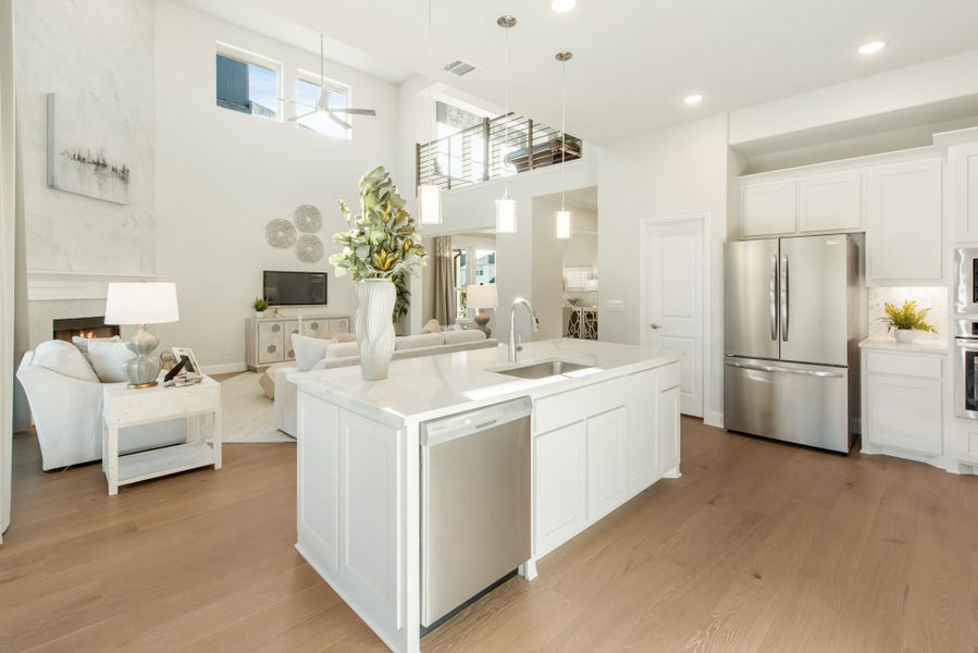 Open-concept kitchen with white island, stainless appliances, and hardwood floors, open to living area with high ceilings