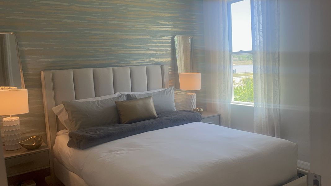 A cozy bedroom featuring a tufted headboard, ambient lighting, and a textured accent wall with serene natural light.