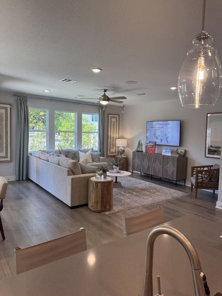 A cozy living room with a plush sectional sofa, sleek wooden floors, and large windows offering abundant natural light.