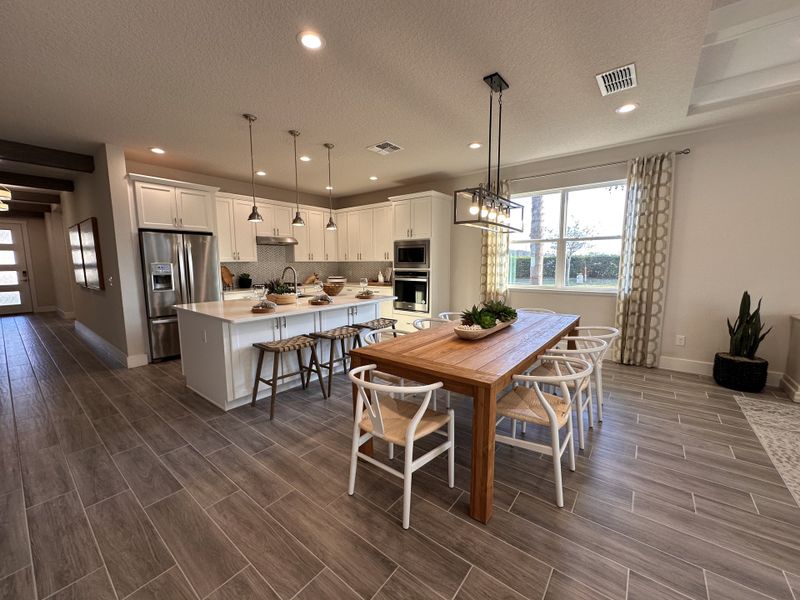 A sophisticated dining room featuring a statement chandelier, bold accent wall, and stylish decor in Crossroads at Kelly Park by Dream Finders Homes (Apopka, FL).