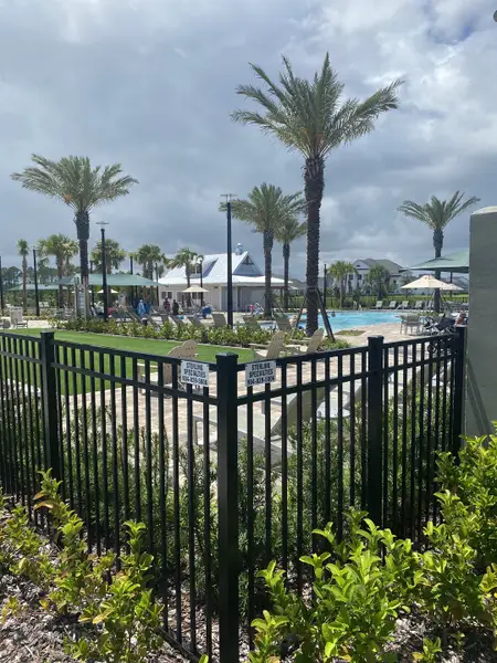 A picturesque community pool with lush landscaping and palm trees in Seven Pines by ICI Homes (Jacksonville, FL).