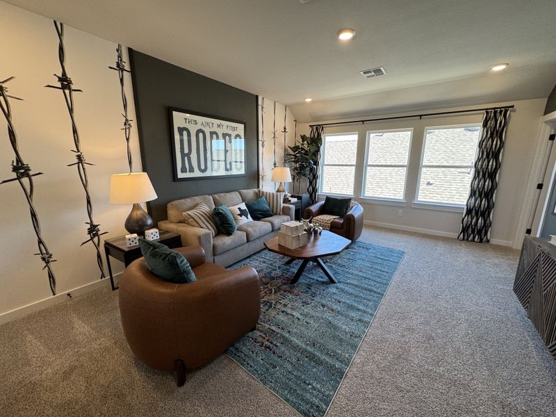 A cozy living room with eclectic decor, featuring a patterned accent wall, stylish furniture, and large windows.