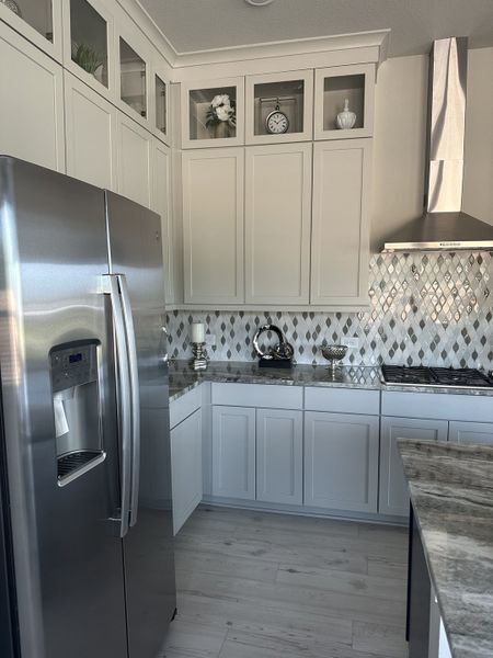 A modern kitchen featuring sleek stainless steel appliances, elegant cabinetry, and a stylish patterned backsplash.