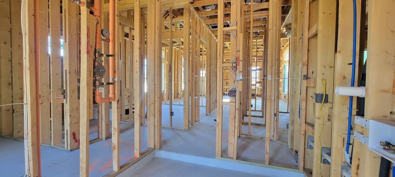 A framed interior showcasing the early stages of construction with exposed wooden beams and visible piping.