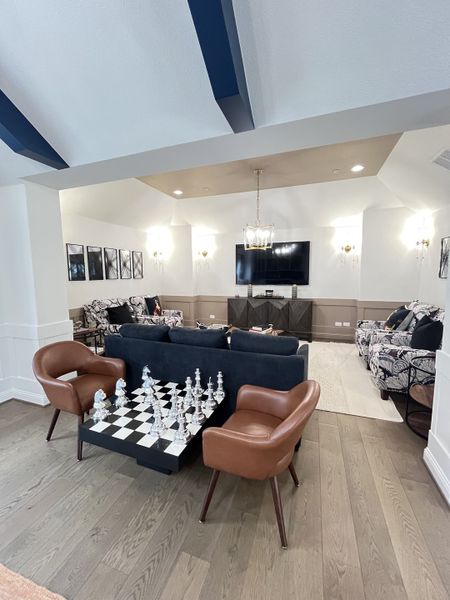 A chic living space featuring a statement chess table, plush seating, and elegant lighting, perfect for relaxation and entertainment.
