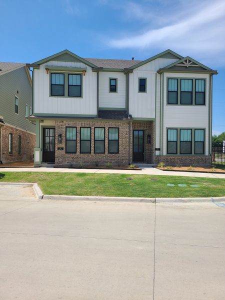 A modern brick and siding home with a neat lawn in Collin Creek by Ashton Woods (Plano, TX).