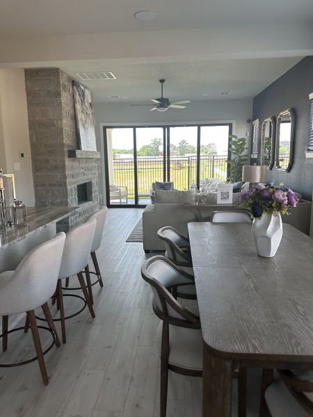 A cozy living area with a stone fireplace, modern dining set, and bright views through large glass doors.