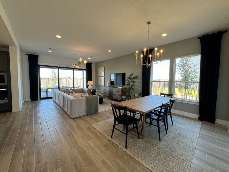 An inviting open-concept living and dining area with large windows, modern lighting, and a cozy, elegant ambiance.