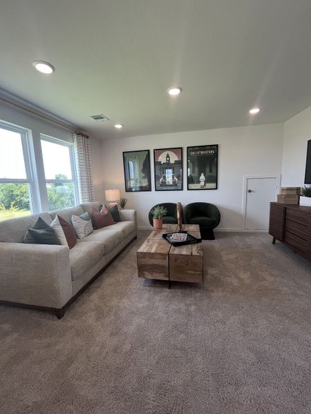 A cozy living room with plush carpet, a large sofa, wooden coffee table, and modern art on the walls.