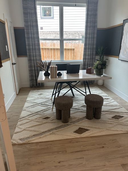 A cozy home office with a sleek desk, modern decor, and plush stools on a patterned rug. A cozy home office with a sleek desk, modern decor, and plush stools on a patterned rug.