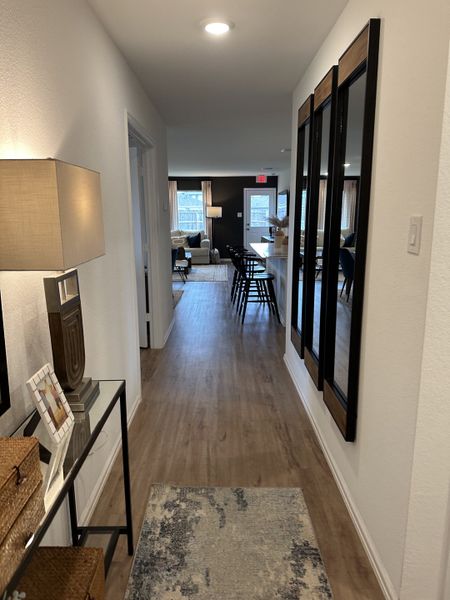 A cozy hallway featuring wooden floors, stylish mirrors, and modern decor leading to an inviting living space. A cozy hallway featuring wooden floors, stylish mirrors, and modern decor leading to an inviting living space.