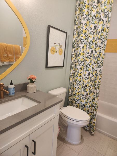 A vibrant bathroom with a lemon-themed shower curtain, warm yellow accents, and a sleek vanity for a cheerful and refreshing space. A vibrant bathroom with a lemon-themed shower curtain, warm yellow accents, and a sleek vanity for a cheerful and refreshing space.