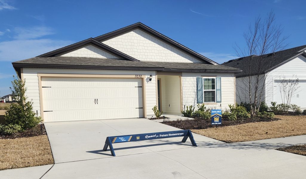 A charming cream home with blue shutters and manicured lawn in Rolling Hills by LGI Homes (Green Cove Springs, FL).