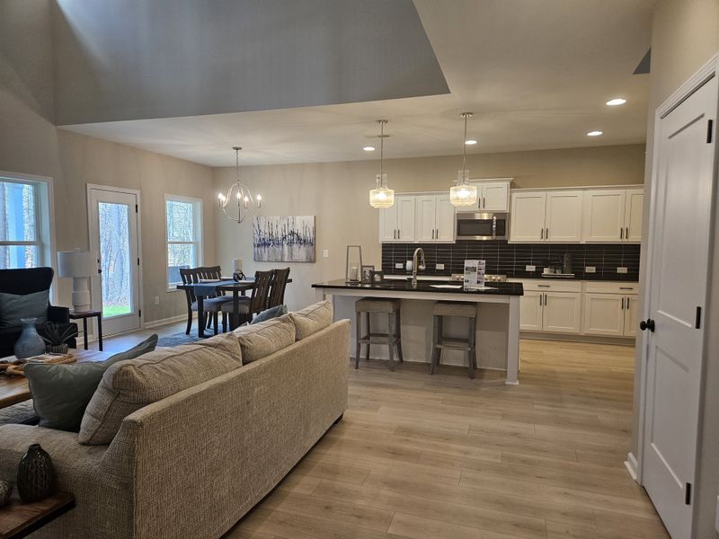 A contemporary open-concept kitchen and living space with pendant lights and a dining area.