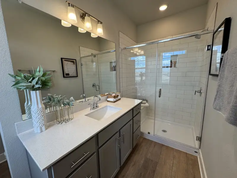 A modern bathroom with sleek quartz countertops, a spacious glass shower, and elegant lighting fixtures.