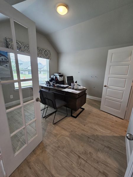 A cozy home office with a large window, wooden flooring, and a sleek dark desk, perfect for productivity. A cozy home office with a large window, wooden flooring, and a sleek dark desk, perfect for productivity.