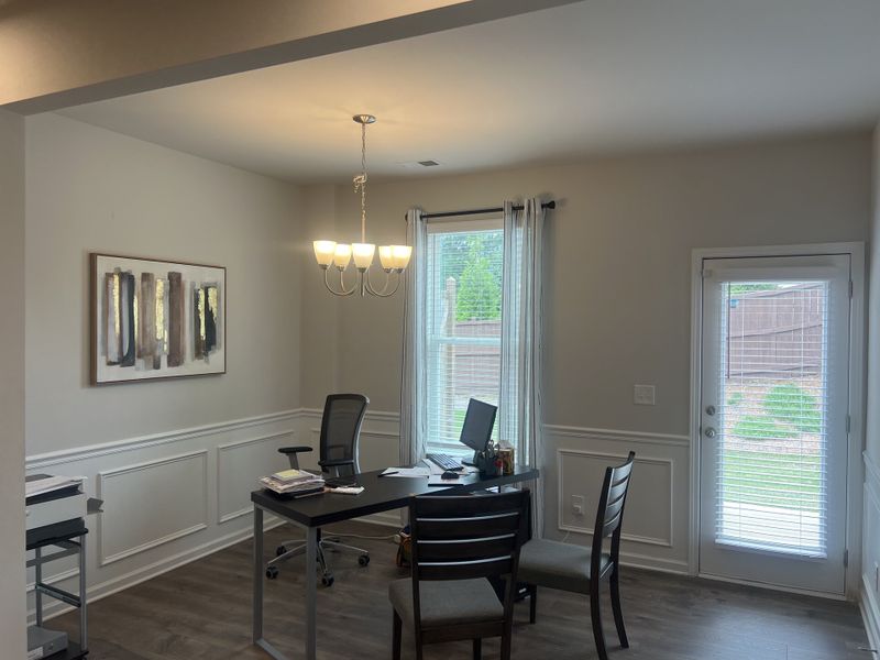 A bright office space with elegant wainscoting, modern lighting, and large windows overlooking the backyard. A bright office space with elegant wainscoting, modern lighting, and large windows overlooking the backyard.