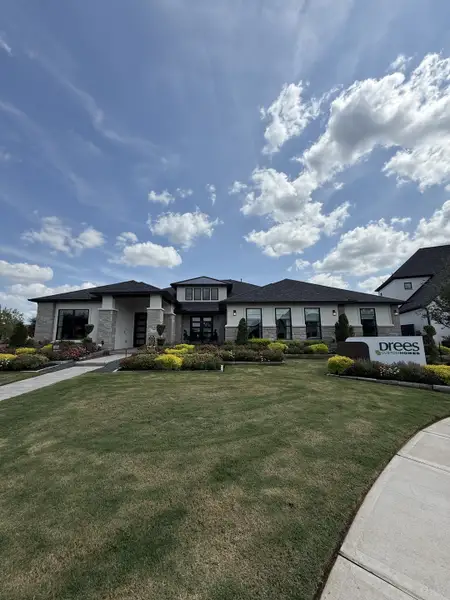 A modern stone-accented home with lush landscaping in Meridiana 80' by Drees Custom Homes (Manvel, TX).