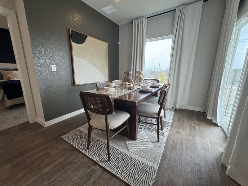 A modern dining area featuring a dark wood table, artistic wall decor, and large windows with flowing curtains. A modern dining area featuring a dark wood table, artistic wall decor, and large windows with flowing curtains.