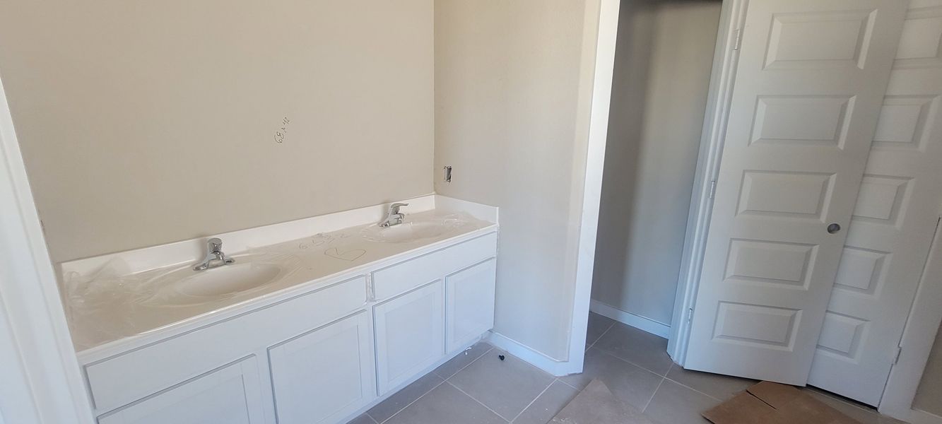 A modern bathroom with a double sink vanity, sleek faucets, and neutral tiles, offering a clean and elegant space.