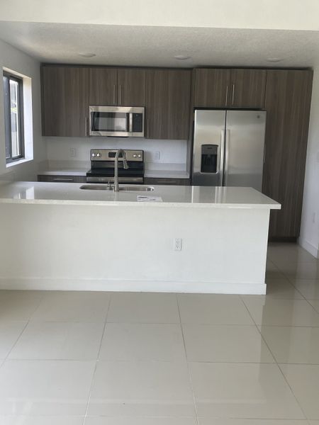 A modern kitchen with sleek cabinetry, stainless steel appliances, and a spacious white countertop.