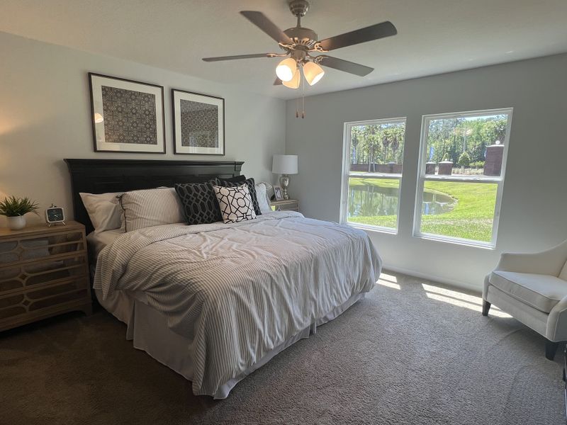 A cozy bedroom with a plush carpet, elegant bed, stylish artwork, and large windows overlooking a serene garden view. A cozy bedroom with a plush carpet, elegant bed, stylish artwork, and large windows overlooking a serene garden view.