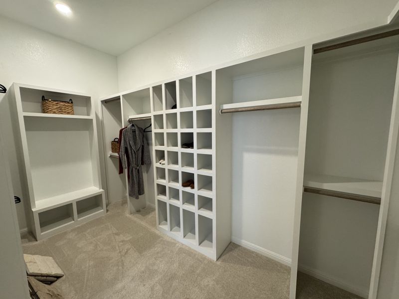 A spacious walk-in closet with open shelving, hanging rods, and plush carpeting for organized storage.