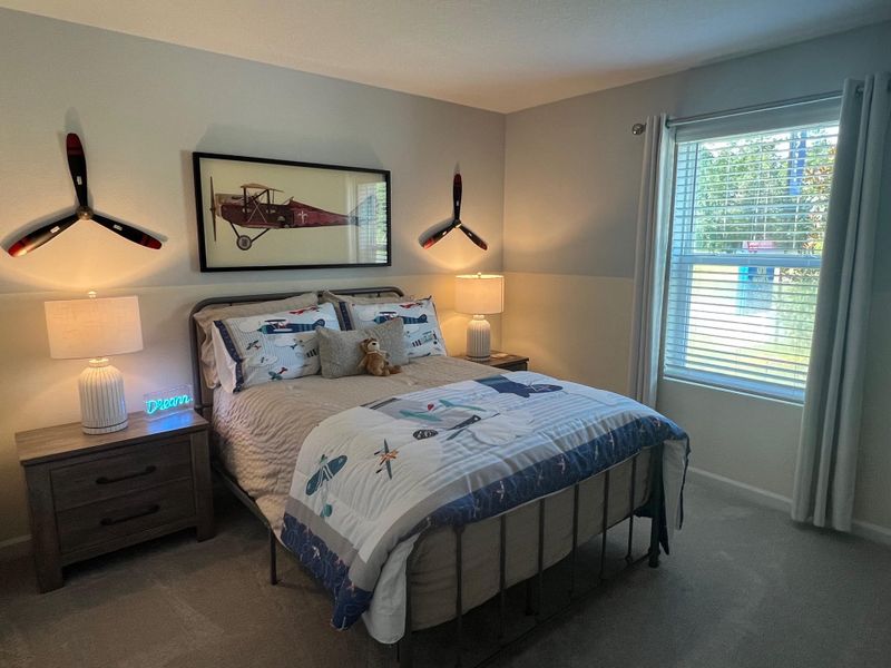 A cozy bedroom with aviation decor, featuring a plane-themed bedspread, propeller wall art, and a framed vintage airplane print.