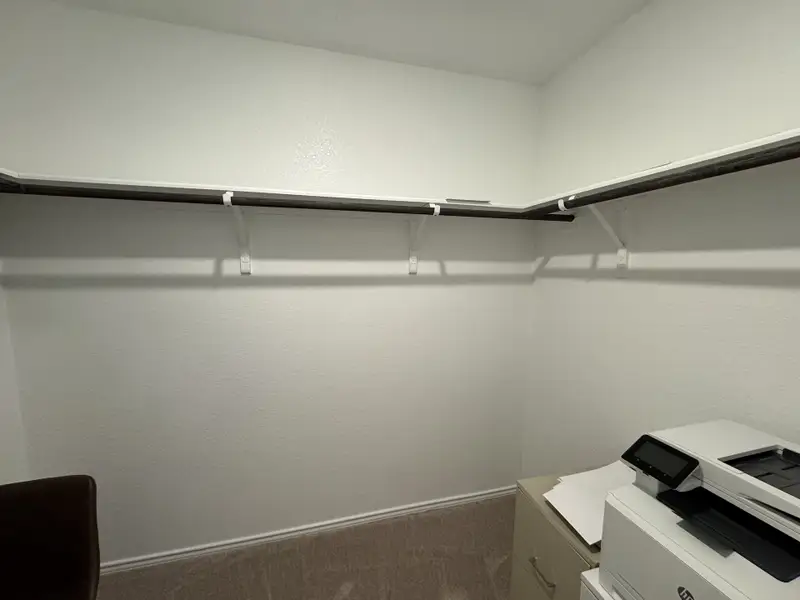 A spacious walk-in closet with ample shelving and a modern printer setup, offering convenience and organization.