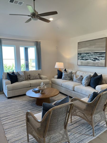 A cozy living room features plush sofas, wicker chairs, and a round wooden table, complete with soft lighting and serene artwork. A cozy living room features plush sofas, wicker chairs, and a round wooden table, complete with soft lighting and serene artwork.