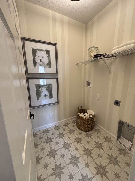 A cozy laundry room with star-patterned tile flooring, framed dog portraits, and neatly organized shelving.