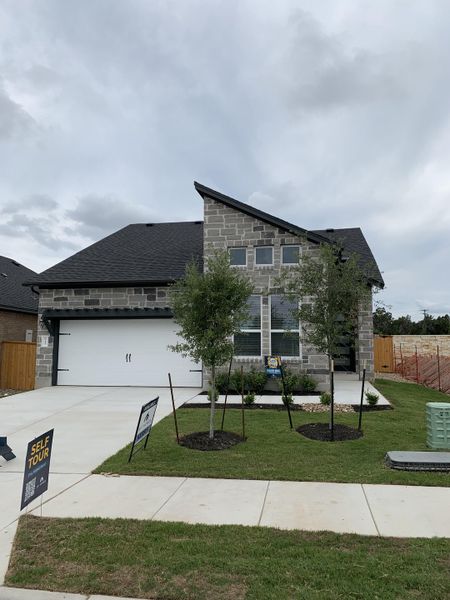 A contemporary stone-clad home with lush landscaping in Cedar Brook by M/I Homes (Leander, TX).