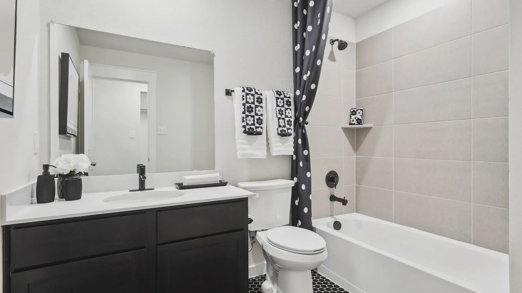 Experience timeless elegance with sleek black vanity and hex tile flooring in Simpson Crossing's luxurious bathroom.