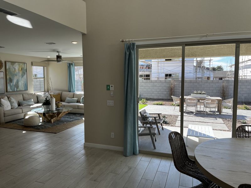 Spacious living room with natural light, a sliding glass door opening to a patio with a seating area and outdoor decor.