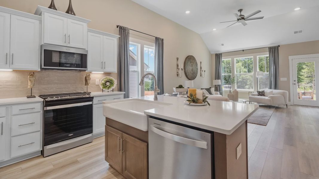 Summit floorplan kitchen with white cabinetry, island with room for counter stools, and farmhouse sink at Pleasant Falls