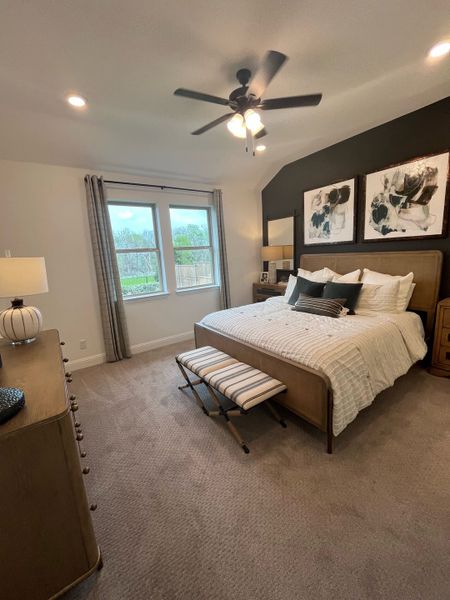A cozy bedroom with neutral tones, a plush bed, and modern art, accented by a ceiling fan and natural light. A cozy bedroom with neutral tones, a plush bed, and modern art, accented by a ceiling fan and natural light.